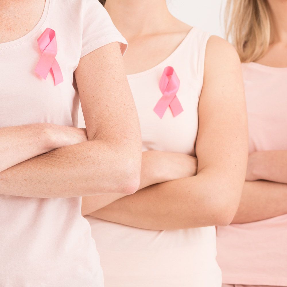 Woman wearing breast cancer ribbon with arms crossed